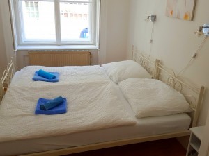 Doppelbett mit weißer Bettwäsche mit blauen Handtücher Wien