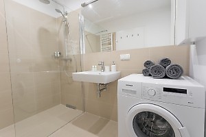 Bathroom with brown tiles, glass shower enclosure in apartme