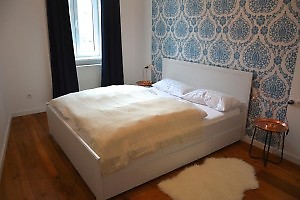 Schlafzimmer mit Doppelbett und blauer Mustertapete