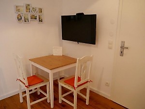 gemütlicher Essplatz und 2 Stühle mit orangenen Sitzflächen