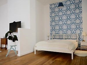 Schlafzimmer mit Doppelbett und lauer Tapete in Fewo Wien