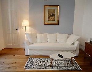 weißes 3 Sitzer Sofa mit bunten Teppich in Unterkunft Wien