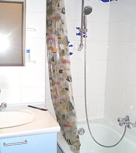 Badezimmer mit Badewanne und Duschvorhang mit bunten Fischen