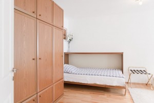 ein ausklappbares Bett an der Wand und großer Schrank